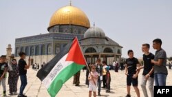 مسجد الاقصی کے سامنے چند فلسطینی نوجوان اپناپرچم لہرا رہے ہیں۔ 21 مئی 2021