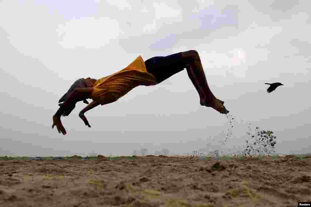 A boy practices somersaulting as he exercises at a beach in Kochi, India.