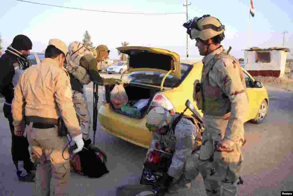 Security personnel search the vehicle of a resident who is fleeing violence in Anbar province at a checkpoint in Ein Tamarm, Jan. 6, 2014. 