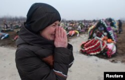 Người thân của nạn nhân thiệt mạng do trúng pháo khóc thương tại một nghĩa trang ở thành phố cảng Mariupol, Ukraine, 27/1/2015.