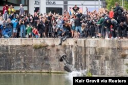 FILE - The statue of 17th century slave trader Edward Colston falls into the water after protesters pulled it down during a protest against racial inequality, in Bristol, Britain, June 7, 2020. (Keir Gravil via Reuters)