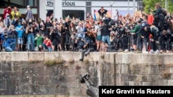 FILE - The statue of 17th century slave trader Edward Colston falls into the water after protesters pulled it down during a protest against racial inequality, in Bristol, Britain, June 7, 2020. (Keir Gravil via Reuters) 