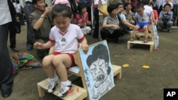 지난해 6월 북한 평양에서 열린 국제 아동절 기념 행사에서 어린이들이 게임 도중 박근혜 한국 대통령과 바락 오바마 미국 대통령을 그린 그림을 깔고 앉았다. (자료사진)