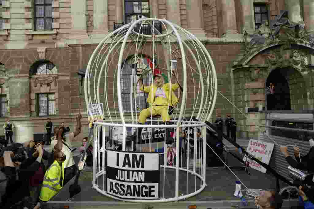 Fashion designer Vivienne Westwood sits suspended in a huge bird cage outside the Old Bailey court, in London, in protest against the extradition of WikiLeaks founder Julian Assange to the U.S.