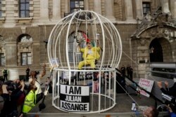 Perancang busana Vivienne Westwood duduk digantung di sangkar burung raksasa sebagai protes terhadap ekstradisi pendiri WikiLeaks Julian Assange ke AS, di luar pengadilan Old Bailey, di London, Selasa, 21 Juli 2020.