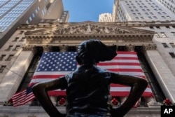 FILE - The New York Stock Exchange is shown behind the statue titled "Fearless Girl" in New York, Dec. 12, 2024.