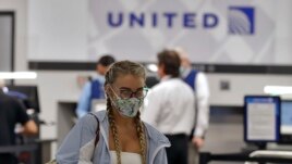 A passenger wearing a protective face mask leaves the United Airlines ticket counter after checking in for a flight at the Tampa International Airport Tuesday, June 16, 2020, in Tampa, Fla. (AP Photo/Chris O'Meara)