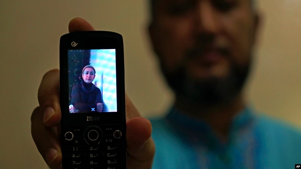 Halmurat Idris holds up a picture of his elder sister, Aug. 24, 2018, at his home in Istanbul, Turkey. Idris says his sisters were monitored as part of a government homestay program, part of a broader crackdown on religious expression in China's far western region of Xinjiang.