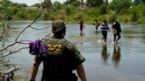 Un agente de la Patrulla Fronteriza observa cómo un grupo de migrantes cruza el Río Bravo camino a entregarse al cruzar la frontera entre Estados Unidos y México, en Del Rio, Texas, el 15 de junio de 2021.