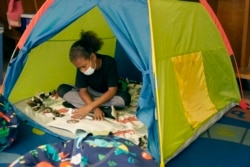 Fifth grader Jordan Falconbury reads inside a tent while visiting a sensory room at Quincy Elementary School, Wednesday, Nov. 3, 2021, in Topeka, Kan. (AP Photo/Charlie Riedel)