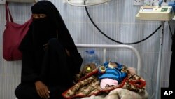 A woman sits next to her malnourished baby at a therapeutic feeding center in a hospital in Sanaa, Yemen, Jan. 24, 2016. 