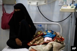 A woman sits next to her malnourished baby at a therapeutic feeding center in a hospital in Sanaa, Yemen, Jan. 24, 2016.