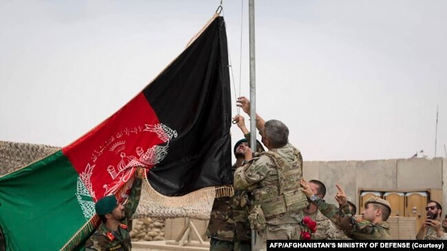 افغان سولجر ایک اڈے کا کنٹرول سنبھالنے کے بعد ملکی پرچم بلند کر رہے ہیں (رائٹر فوٹو)