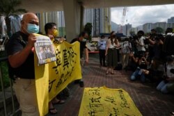 Pro-democracy activists holding a copy of Apple Daily newspaper and banner protest outside a court in Hong Kong, Saturday, June 19, 2021, to demand to release political prisoners.