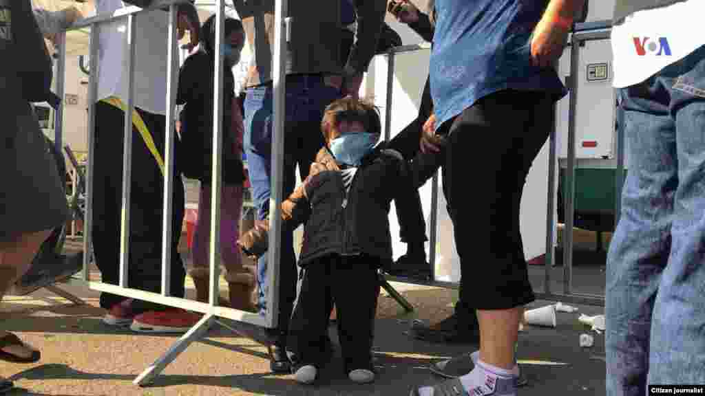 Un niño es visto de la mano de una mujer en un albergue improvisado en Tijuana, donde se encuentran los migrantes esperando entrar a EE.UU.&nbsp; Fotografía: Celia Mendoza- VOA