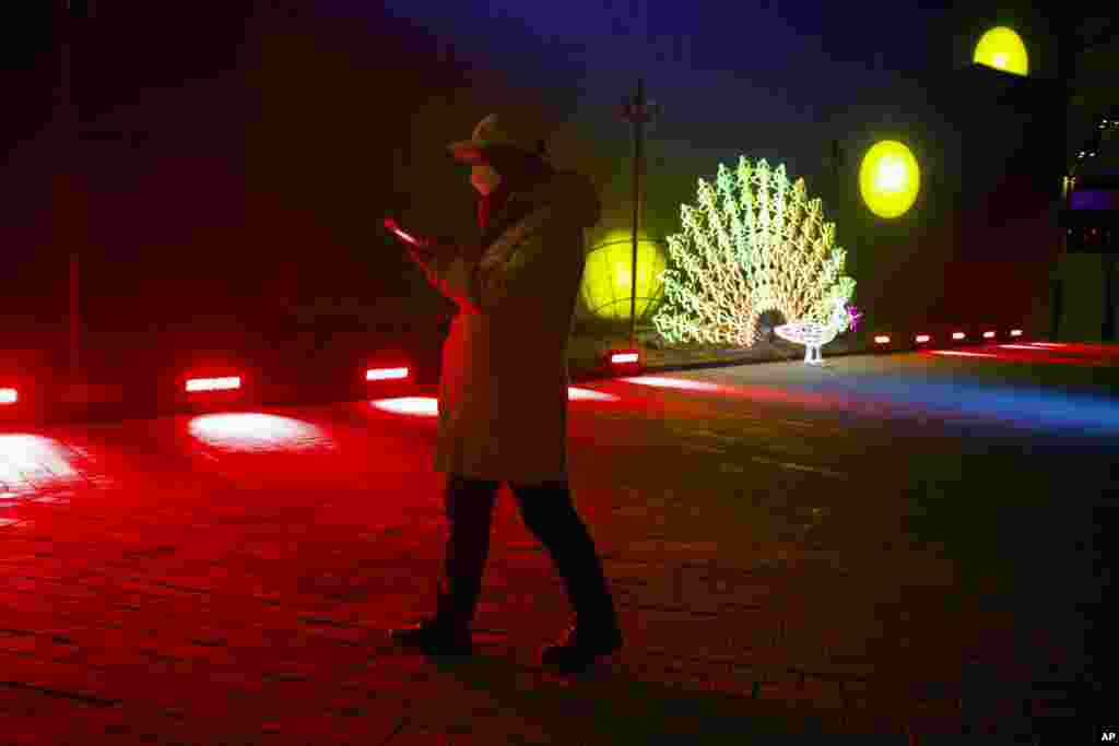 Un hombre camina el 31 de diciembre de 2019 cerca a una escultura de luz antes del conteo de año nuevo en el las instalaciones de los Juegos Olímpicos de Invierno de Bejing (2022).