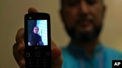 Halmurat Idris holds up a picture of his elder sister, Aug. 24, 2018, at his home in Istanbul, Turkey. Idris says his sisters were monitored as part of a government homestay program, part of a broader crackdown on religious expression in China's far western region of Xinjiang.