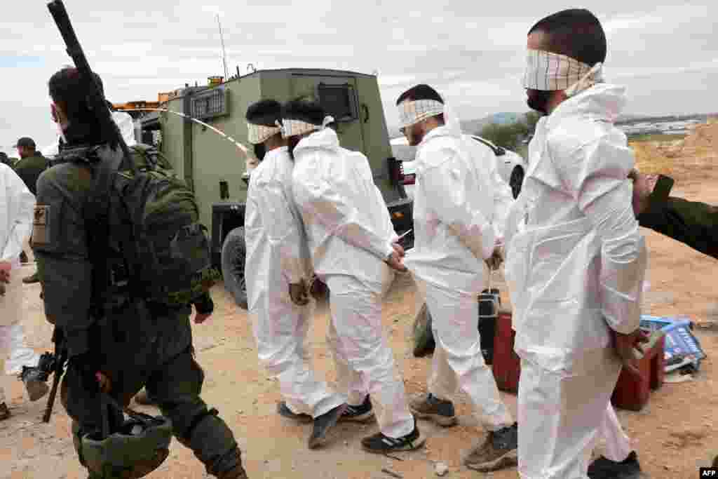 Israeli soldiers transfer Palestinian men arrested during a military raid in Jenin, near the Muqeibila crossing on the border with the occupied-West Bank. Gunfire and explosions rocked the Jenin area, an AFP journalist reported, as the Israeli military kept up a large-scale raid for a second day.