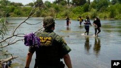 Un agente de la Patrulla Fronteriza observa cómo un grupo de migrantes cruza el Río Bravo camino a entregarse al cruzar la frontera entre Estados Unidos y México, en Del Rio, Texas, el 15 de junio de 2021.