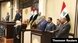 The speaker of Iraq's parliament Mohammed al-Halbousi stands with newly appointed ministers during a swearing-in ceremony at the parliament headquarters in Baghdad, June 24, 2019.