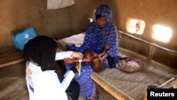 FILE - Volunteer health worker Ashwaq Muharram measures the arm of a girl to assess her nutritional status in Abs, Yemen, August 31, 2021.