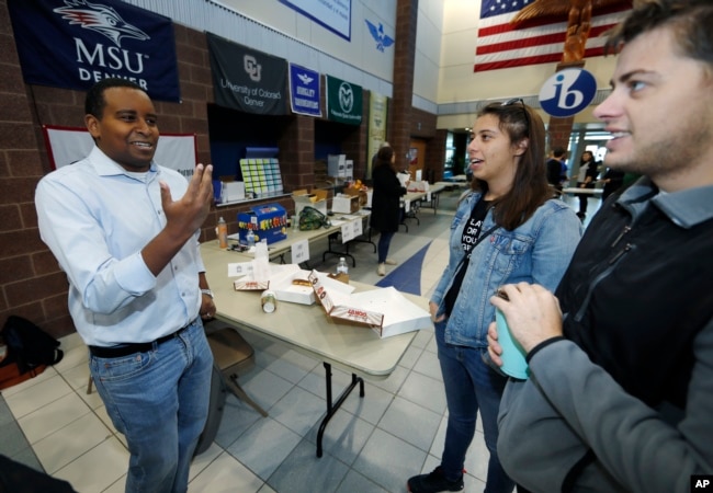 Democratic candidate Joe Neguse for U.S. House District 2, left, greets canvassers as they head out to round up votes from Hinkley High School, Oct. 20, 2018, in Aurora, Colo.