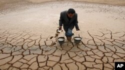 A farmer takes water form a dried-up pond to water his vegetable field on the outskirts of Yingtan, Jiangxi province December 10, 2007. Climate change has been blamed for more frequent droughts in some regions.