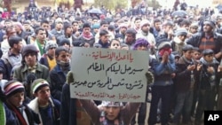 Demonstrators take part in a protest against Syria's President Bashar al-Assad - carrying a sign that reads, 'Enemies of humanity your dark night will go and the new dawn of freedom will rise' - in Jerjenaz, near Idlib, February 17, 2012.