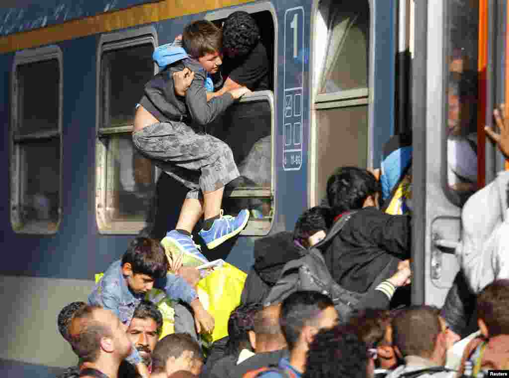 Migrants storm onto a train at the Keleti train station in Budapest, Hungary, as police withdrew from the gates after blocking entry for two days, Sept. 3, 2015.
