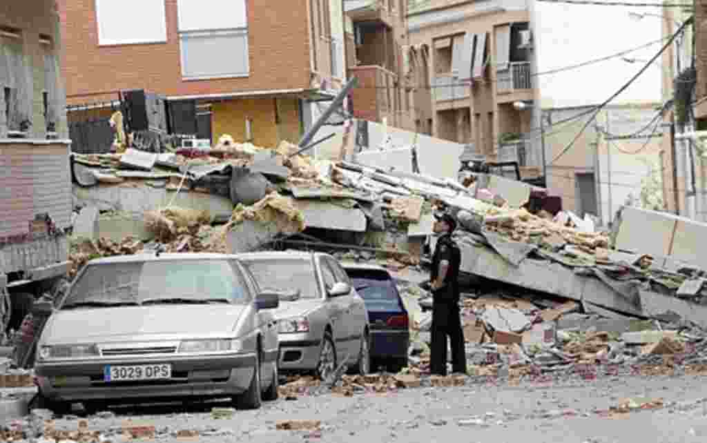 A police officer looks at the damage in Lorca, Spain a day after an earthquake hit the region, May 12, 2011.