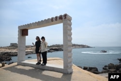 Tourists pose for photos as they visit a scenic spot on Pingtan island, the closest point in China to Taiwan’s main island, in Fujian province on May 18, 2024.