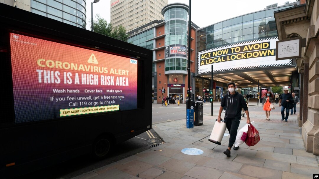 Para pengunjung tampak dekat papan informasi di pusat kota Manchester setelah Perdana Menteri Boris Johnson mengumumkan pembatasan baru untuk meredam pandemi virus corona gelombang kedua, di Manchester, Inggris, 22 September 2020. (Foto: AP)