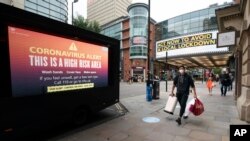 Para pengunjung tampak dekat papan informasi di pusat kota Manchester setelah Perdana Menteri Boris Johnson mengumumkan pembatasan baru untuk meredam pandemi virus corona gelombang kedua, di Manchester, Inggris, 22 September 2020. (Foto: AP)