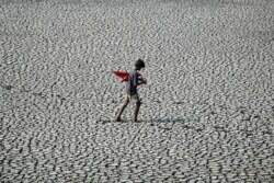 FILE - A youth walks on the parched bed of a temple tank during a hot day in Chennai, India, April 24, 2020.