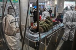 Medical staff members wearing protective clothing to help stop the spread of a deadly virus which began in the city, arrive with a patient at the Wuhan Red Cross Hospital in Wuhan on January 25, 2020.