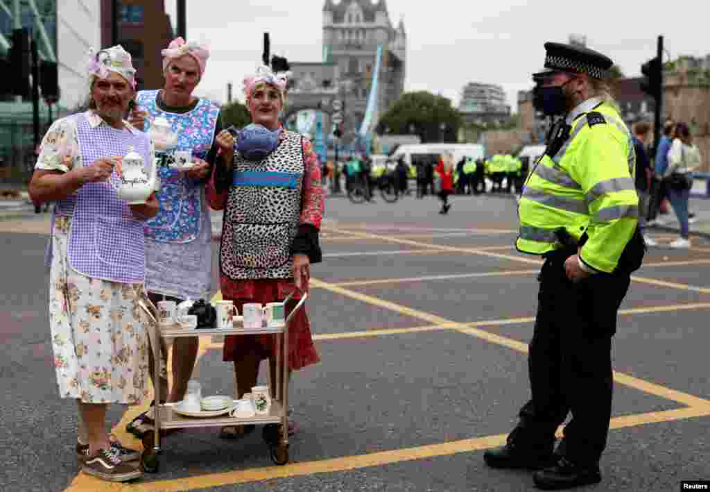 Police officer stands by Extinction Rebellion climate demonstrators during a protest in London, Aug. 30, 2021.