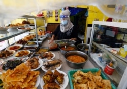 Seorang pekerja di warung makan mengenakan pelindung wajah di tengah pelonggaran PSBB terkait pandemi virus corona (Covid-19), di Jakarta, 28 Juli 2020. (Foto: Reuters)