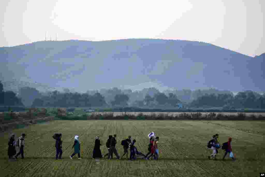 Para migran mendekati pos pemeriksaan perbatasan di kota Idomeni, Yunani, dan menyeberangi Makedonia selatan (3/9). Makedonia telah menanggung arus masif pengungsi dan migrasi orang-orang yang menuju Uni Eropa, dengan lebih dari 200.000 orang tiba di sana sejauh ini tahun ini.​&nbsp;(AP/Giannis Papanikos)