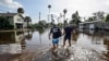 Thomas Chaves, left, and Vinny Almeida walk through floodwaters from Hurricane Helene in an attempt to reach Chaves's mother's house in St. Petersburg, Florida, Sept. 27, 2024.