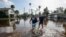 Thomas Chaves, left, and Vinny Almeida walk through floodwaters from Hurricane Helene in an attempt to reach Chaves's mother's house in St. Petersburg, Florida, Sept. 27, 2024.
