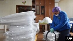 FILE - A civil activist packs suits to protect hospital workers against COVID-19 in Bishkek, Kyrgyzstan, April 15, 2020. 