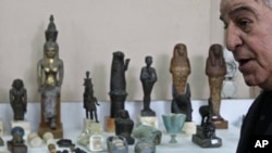 Egypt's Minister of Antiquities Zahi Hawass stands beside damaged artifacts in the Egyptian Museum, located near the opposition stronghold of Tahrir Square, in Cairo, February 10, 2011.