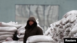 FILE - A man stands among sacks of wheat on the banks of Yalu River near the North Korean town of Sinuiju, opposite the Chinese border city of Dandong, January 29, 2014.