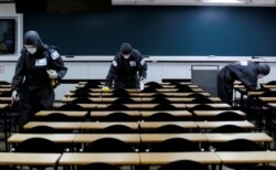 FILE - South Korean soldiers clean desks with disinfectant in a classroom of a cram school for civil service exams, following the rise in confirmed cases of coronavirus disease (COVID-19) in Daegu, South Korea, March 15, 2020.