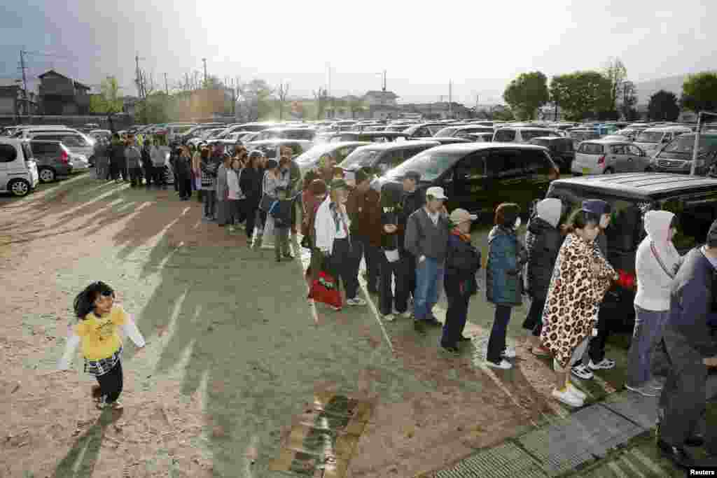 People line up to get food and water supplies at an elementary school after an earthquake in Mashiki town, Kumamoto prefecture, in this photo taken by Kyodo April 17, 2016.