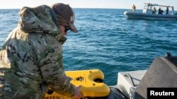 A U.S. Navy sailor conducts a search for debris of a high-altitude Chinese balloon shot down by the U.S. Air Force off the coast of South Carolina on Feb. 7, 2023. 3 more objects, downed the next week over the U.S. and Canada, remain unrecovered.