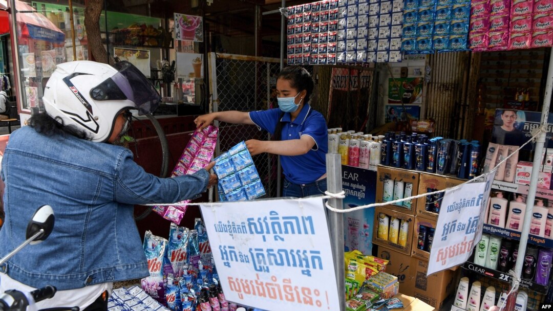 FILE - A vendor shows sachets of hair shampoo to a customer from a shop that has been marked off to allow for social distancing, as a preventive measure against the spread of the COVID-19 novel coronavirus, in Phnom Penh, May 27, 2020. 