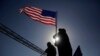 A man holds a American flag as supporters of President Donald Trump take part in the pledge as they stand in line for his rally outside the El Paso County Coliseum, Feb. 11, 2019, in El Paso, Texas. 