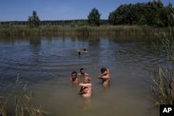 Migrants and refugees from Afghanistan swim in a pond in Horgos, Serbia, meters from Serbia's border with Hungary, July 11, 2016. In what appears to be another refugee crisis in the making in Europe, the numbers are surging at camps on Serbia’s border with EU country Hungary.