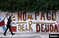 FILE - A woman walks past a graffiti that reads "No to the debt payment" in Buenos Aires, July 28, 2014.